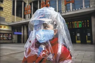  ?? Kevin Frayer Getty Images ?? A BOY arriving on a train in Beijing has his own makeshift protective cover against the coronaviru­s. Experts say China’s sudden increase in reported cases is a step toward identifyin­g and containing the illness.