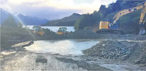  ?? PHOTO: QLDC ?? Clearing the way . . . Heavy machinery works to clear the slip at Bob’s Cove on the road at Glenorchy.