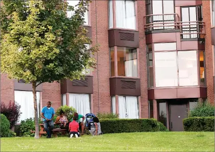  ?? CP PHOTO ?? People relax on the grounds of Cornwall’s Nav Centre, which is temporaril­y housing U.S. asylum seekers, Monday.