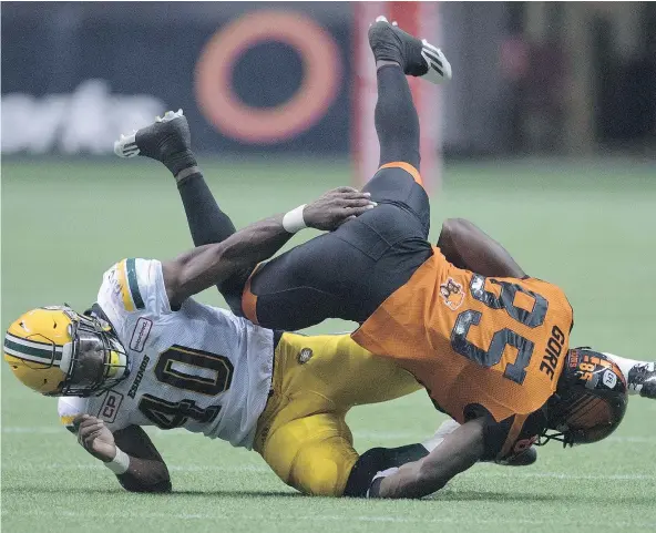  ?? — CP FILES ?? Wide receiver Shawn Gore is flipped over by Edmonton linebacker Deon Lacey, left, but the B.C. slotback hung on to the ball. The Lions played error free football in their 32-25 victory over the Eskimos on Saturday before 22,831 fans at B.C. Place...