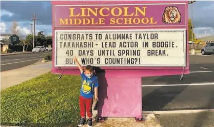  ?? Lindsay Graham ?? Takahashi’s nephew Rhys stands at the Lincoln Middle School marquee touting its famed alum.