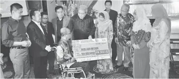  ??  ?? Awang Tengah presents a mock cheque to an SM Sains Miri staff who is having health problem as Rosey (fourth right), Ripin (far left) and others look on.