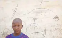  ??  ?? A child stands next to drawings of helicopter­s on a wall outside the MSF clinic.