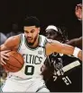  ?? Charles Krupa / Associated Press ?? Boston Celtics forward Jayson Tatum (0) tries to pivot around Milwaukee Bucks guard Jrue Holiday during the first half of Game 5 of an Eastern Conference semifinal Wednesday in Boston.
