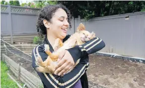  ??  ?? Nadine Saint-Ange holds one of the family dogs in front of her newly planted vegetable garden which she hopes will help feed the family.