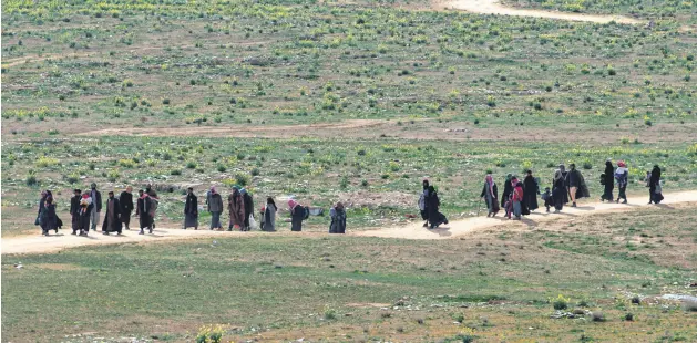  ??  ?? Men believed to be Daesh terrorists and their families walk in a field as they leave the terrorist group’s last territory, the village of Baghouz, Feb. 13, 2019.