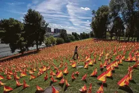  ?? Manu Fernandez / Associated Press ?? A woman walks among the 53,000 flags placed in a Madrid, Spain, park in memory of the nation’s coronaviru­s victims on Sunday.