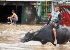  ??  ?? In deep water: People wading through a flooded street in the town of Baao in Camarines Sur. — AFP