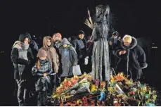  ?? FOTO: SERGEI CHUZAVKOV/AFP ?? Menschen in Kiew zünden Kerzen an und legen Blumen am Denkmal für die Opfer des Holodomor nieder, der Großen Hungersnot, die in den 1930er-Jahren stattfand und der Millionen Menschen zum Opfer fielen.