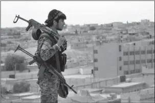  ?? The Associated Press ?? SYRIA: This April 30, 2017 photo provided by the Syria Democratic Forces (SDF), shows a fighter from the SDF carrying weapons as he looks toward the northern town of Tabqa, Syria. U.S.-backed Syrian forces say the battle for control of the Islamic...