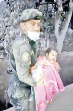  ?? — Reuters photo ?? A soldier rescues a girl from a hole in an area affected by the eruption of Fuego volcano in Escuintla, Guatemala.