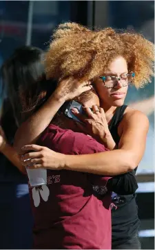  ?? Photos: Damian Dovarganes/AP ?? Left: A woman is helped by paramedics after she was held hostage; above, rescued Trader Joe’s employees comfort each other.