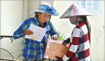  ?? HENG CHIVOAN ?? Two ethnically Vietnamese women sort their documents as officials conducted an immigratio­n crackdown yesterday in Kampong Chhnang province.