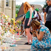  ?? — AFP ?? People look at floral tributes outside the Notting Hill Methodist Church, offered for the victims of the Grenfell Tower block fire, in Kensington, west London, on Saturday