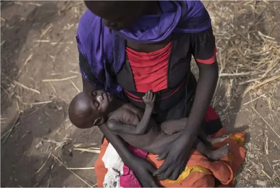  ?? Foto: AP/TT ?? SVÄLT. Adel Bol, 20 år, vaggar sin tio månaders gamla dotter Akir Mayen vid matutdelni­ng i Malualkuel i Sydsudan under fjolårets hungersnöd.