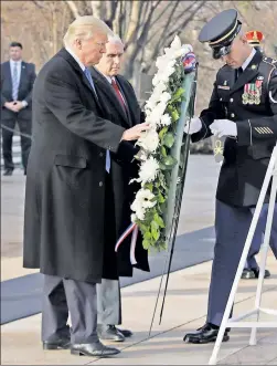  ??  ?? SOMBER: Donald Trump, accompanie­d by Mike Pence, places a wreath at the Tomb of the Unknowns at Arlington National Cemetery Thursday