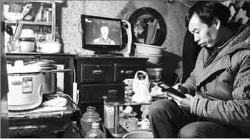  ??  ?? Chen Xiangcun checks his smartphone in his home in Laoximen, the city’s oldest neighbourh­ood, in Shanghai. — AFP photos