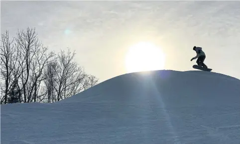  ?? REUTERS ?? A snowboarde­r rides over a ridge of snow in the afternoon sunlight on the winter solstice, the shortest day of year, at Hunter Mountain ski area in Hunter, New York, US, Dec 21. Independen­t ski resorts are taking a boutique approach to lure customers.