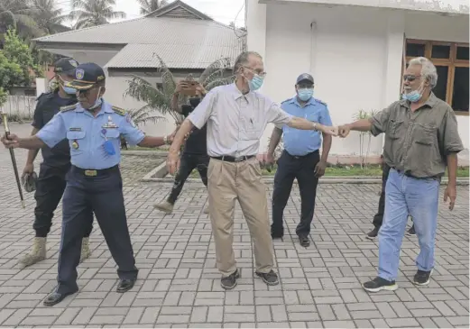  ?? RAIMUNDOS OKI/AP ?? Xanana Gusmao (right), former East Timorese president and prime minister, gives a fist bump to Richard Daschbach (center), a defrocked priest on trial on child abuse charges, after a hearing at a courthouse in Oecusse, East Timor on Feb. 23. Daschbach’s support appears deep and widespread.