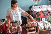  ??  ?? Dorina Hanza, a 52-year-old embroidere­r, shows two traditiona­l outfits from the Bihor northweste­rn region of Romania in Beius, Romania.— AFP photos