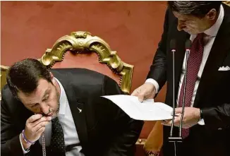  ?? Andreas Solaro/AFP ?? Matteo Salvini (esq.) beija rosário ao lado de Giuseppe Conte