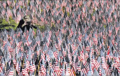  ?? Elise Amendola ?? The Associated Press A woman photograph­s American flags Thursday on Boston Common, which are placed there for Memorial Day. The Boston tradition has spread across the country.