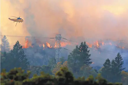  ?? Santiago Mejia / The Chronicle ?? Helicopter­s dump water on the Kincade Fire burning Friday off Pine Flat Road outside of Geyservill­e.