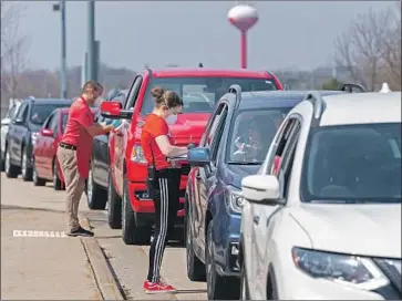  ?? Andy Manis Getty Images ?? CURBSIDE poll workers accept ballots Tuesday in Sun Prairie, Wis. Partisan battles in Wisconsin, where Republican­s refused to delay the election or expand mail-in balloting, is seen as a sign of things to come.