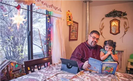  ?? GABRIELA CAMPOS/THE NEW MEXICAN ?? Jose Martinez, 39, reads Friday to his 2-year-old daughter, Gabriella Martinez, at their kitchen table in Cordova. Martinez has been learning to read with a tutor over the past four years, and was motivated to learn so he would be able to read both the Bible and stories to his young daughter.