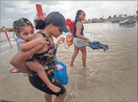  ?? Ap-stuart Villanueva ?? Stacey Young gives her daughter, Kylee Potts, a piggyback ride across the flooding Stewart Beach parking lot in Galveston, Texas on Saturday. Tropical Storm Beta continues to move through the Gulf of Mexico and is expected to bring tidal surge and heavy rain to the area.