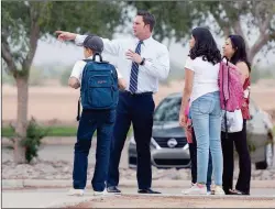  ??  ?? CRANE MIDDLE SCHOOL Principal Ryan Tyree (second from left) helps a mother and her children navigate the school campus early Tuesday morning.