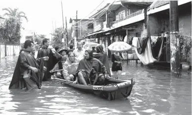  ??  ?? UNITY IN CALAMITY – Officials of Barangay Zapote in Las Piñas help people pass through a flooded road using rescue boats as ‘Maring’ poured heavy rains yesterday. (Ali Vicoy)