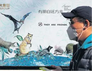  ?? Picture: Shuttersto­ck. ?? A man wearing a protective face mask walks by a poster promoting the protection of wildlife.