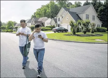  ?? STEVE SCHAEFER / SPECIAL TO THE AJC ?? Volunteer Jongwon Lee (left) and Asian Americans Advancing Justice program associate Raymond Partolan walk through a Johns Creek neighborho­od. They talked with residents about the new voter registrati­on deadline.