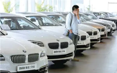  ?? — Reuters ?? A man takes a look at second-hand BMW cars at a dealer shop in Beijing, China.