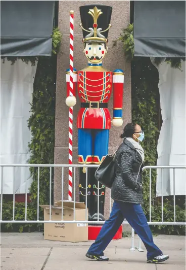  ?? Peter J. Thompson / National Post ?? Christmas decoration­s are being set up outside of Hudson’s Bay flagship store in Toronto on Thursday. Health officials have warned that merry-making may be curtailed.