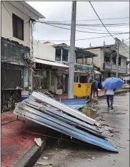  ?? (AP/Daniel Parra) ?? People walk past a damaged building in the aftermath of Hurricane Julia Sunday in San Andres island, Colombia.