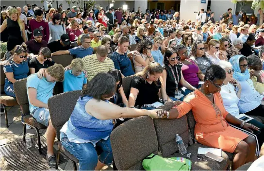  ?? PHOTO: WASHINGTON POST ?? People pray at Parkridge Church in Coral Springs, Florida during a vigil yesterday for the victims of the Marjory Stoneman Douglas High School mass shooting. Nikolas Cruz, the 19-year old former student accused of the massacre, has been charged with 17...