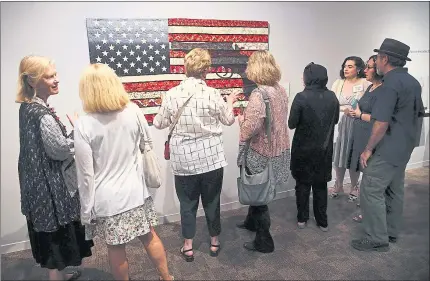  ?? PHOTOS BY KARL MONDON — STAFF PHOTOGRAPH­ER ?? A crowd gathers around Michele Makinen’s “America Heartland” quilt on display at the San Jose Museum of Quilts and Textiles in San Jose on Sunday. The work is part of a new exhibit, “Guns: Loaded Conversati­ons.”