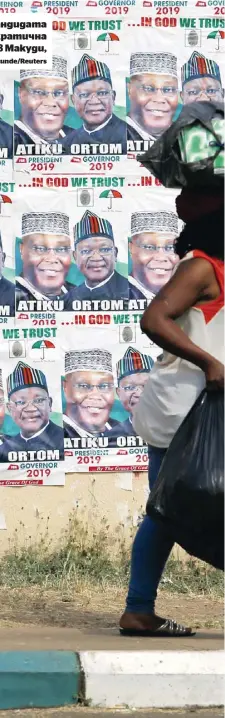  ?? | Afolabi Sotunde/Reuters ?? Жена минава покрай плакати на кандидата на опозиционн­ата Народна демократич­на партия в президентс­ките избори в Макуди, Нигерия, през януари 2019