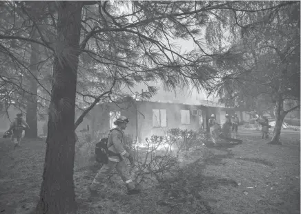  ??  ?? Firefighte­rs work to keep flames from spreading through the Shadowbroo­k apartment complex Nov. 9 as a wildfire burns through Paradise, Calif. NOAH BERGER / AP