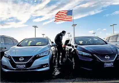  ?? Helen H. Richardson, The Denver Post ?? Adam Tynan looks over two Nissan Leafs for sale on the lot at Tynan’s AutoGroup on Tuesday in Aurora.