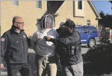  ?? ROBERT RIZZUTO/HAMPDEN COUNTY SHERIFF’S DEPARTMENT VIA AP ?? Rorie S. Woods, 55, of Hadley, Mass., center, wears a beekeeping suit while taken into custody by Hampden County Sheriff’s Department officers, in Longmeadow, Mass., on Oct. 12.