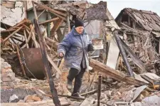  ?? AP ?? A woman carries possession­s from her house destroyed in Russian drone attack in Zaporizhzh­ia on Thursday.