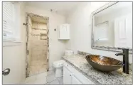  ?? ?? A fully tiled walk-in shower and a vanity with a vessel sink are part of the primary bath.