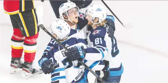  ?? JASON FRaNSON/THE CANADIAN PRESS ?? The Jets celebrate after Nikolaj Ehlers scored the game-winning goal against the Flames in the third period of Monday’s contest in Edmonton.