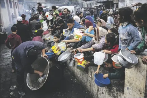  ?? FATIMA SHBAIR/ASSOCIATED PRESS ?? PALESTINIA­NS LINE UP FOR A FREE MEAL IN RAFAH, GAZA STRIP, on Thursday. Internatio­nal aid agencies say Gaza is suffering from shortages of food, medicine and other basic supplies as a result of the two and a half month war between Israel and Hamas.