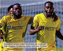  ?? ?? Mustapha Carayol (right) celebrates his stoppageti­me equaliser for Burton Albion with Deji Oshilaja.