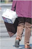  ?? FOTO: SEBASTIAN KAHNERT/DPA ?? Eine Passantin trägt eine Packung Klopapier: Für den Handel ist das Hamstern nicht unproblema­tisch.