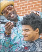  ??  ?? Barber Jeff Johnson (left) cuts Moise’s hair.